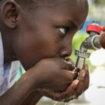 boy drinking from outdoor water facet