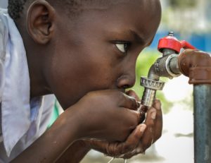 boy drinking from outdoor water facet