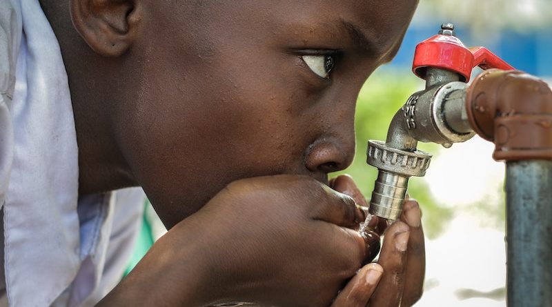 boy drinking from outdoor water facet